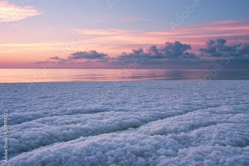 Frozen ice crystals resting on a tranquil beach at sunset with soft pastel clouds and macro detail for winter travel and environmental marketing