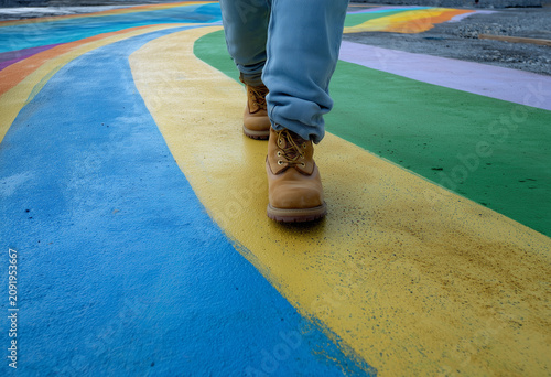 Person walks on colorful path with rainbow stripes in an outdoor space during daylight