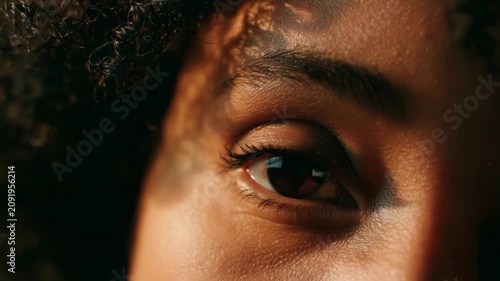 Close up of black woman eye opening in warm light, concept for awakening and inner transformation
