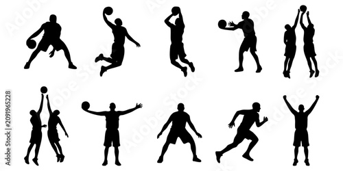 A group of people playing basketball in various poses on the court indoors.