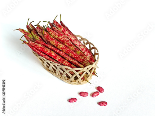 Fotografie Fresh borlotti bean pods (Phaseolus vulgaris) in a woven rattan basket with a fe