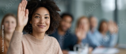 Diverse group in classroom with one person raising hand to speak