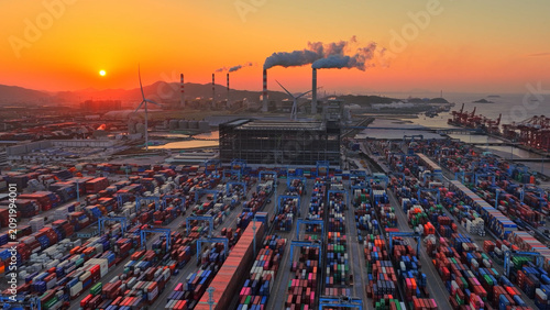 Industrial port area large shipping cargo containers sunset. Fossil fuel power plant air smoke stacks, wind turbine. Global logistics trade industry terminal. Windmill energy factory. Smoking chimneys