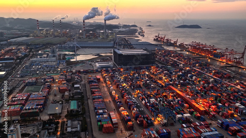 Industrial port area large shipping cargo containers sunset. Fossil fuel power plant air smoke stacks, wind turbine. Global logistics trade industry terminal. Windmill energy factory. Smoking chimneys