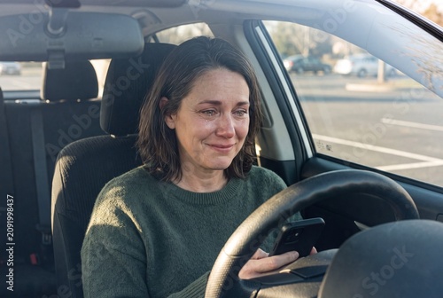Woman in Her 40s Sitting Alone in Car Reading Text Message with Glistening Eyes and Relieved Half-Smile