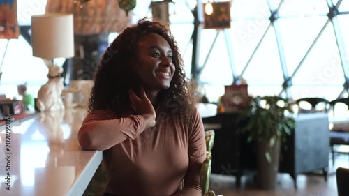 Confident successful young African American woman relaxing at the bar counter of a restaurant