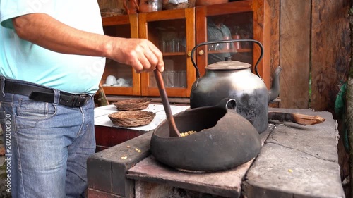 Man roasting coffee beans in a rustic kitchen stove