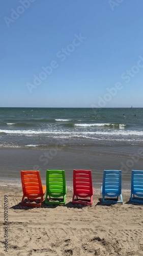 serie di sedie in plastica colorata in riva al mare