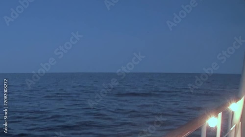 Witness majestic Arctic Ocean at dusk from cruising vessel. Gentle ripples softly break on calm water surface as distant horizon merges with muted sky. Peaceful northern passage unfolds.