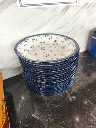 stack of blue floral patterned plates on a dark marble countertop in a kitchen.