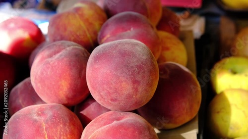 Fresh ripe peaches with nectarines and lemons displayed at local farmers market on sunny summer day, colorful seasonal fruit selection, healthy organic produce ready for sale