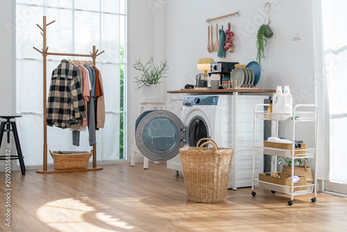 Laundry room washing machine basket drying rack clothing bright interior with wood floor, cart, detergent bottle, shelf, window, calm domestic cleaning space