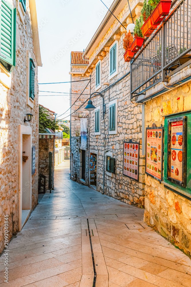 Naklejka premium Scenic coastal promenade and the old stone town of Primosten under a clear blue sky, Dalmatia, Croatia.