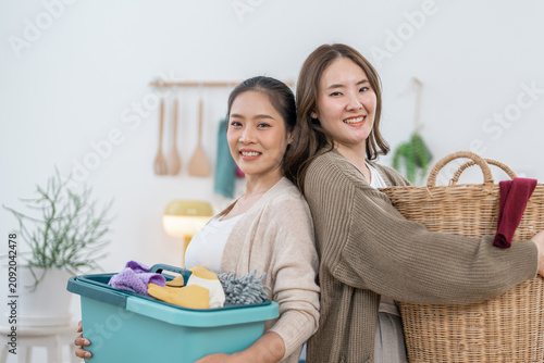 Asian woman, laundry basket, wicker basket, smile, home cleaning partners holding fabric container and household clothes in bright room, cheerful domestic chore concept