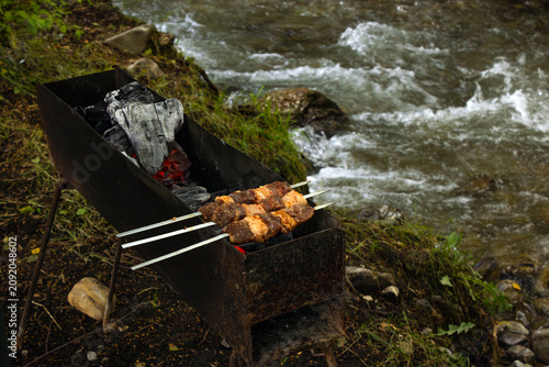 Tableau sur toile Cooking marinated shashlik on a homemade grill by the river