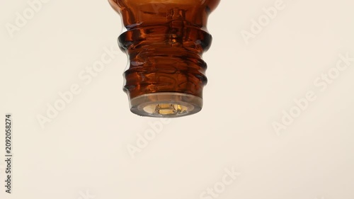 A close-up of a glass bottle containing serum and essential oil for aromatherapy. Drops, macro view from the front.