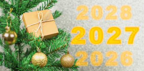 Happy New Year 2027 anniversary. Transition from 2026 to new year 2027 concept image with golden ball ornament on Christmas tree.