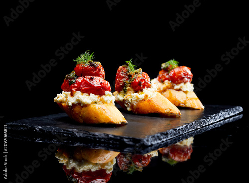 Bild auf Leinwand A gourmet bruschetta appetizer topped with roasted cherry tomatoes, creamy ricot