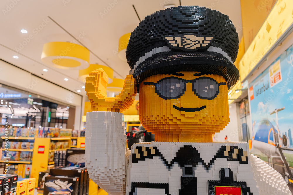 Obraz premium Large LEGO figure of a police officer with sunglasses and a hat, displayed in a colorful toy store environment
