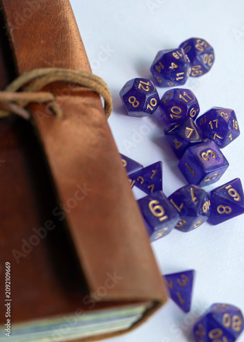 Fotografia Purple roleplaying dices scattered next to a leather-bound adventure journal, ve