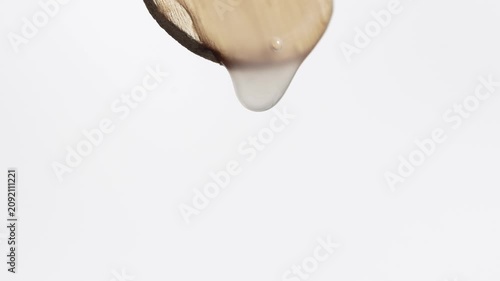 Serum, gel, peptide slowly drips from a wooden spatula, macro.