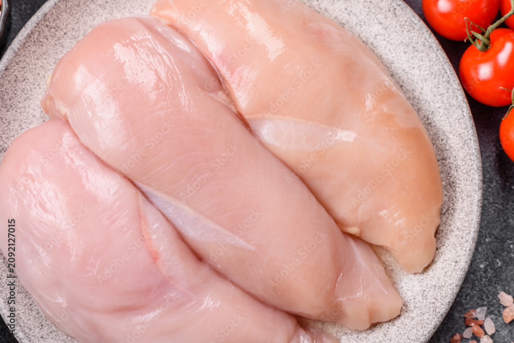 Fototapeta premium Fresh raw chicken fillet with salt and spices for home cooking. Raw chicken fillet