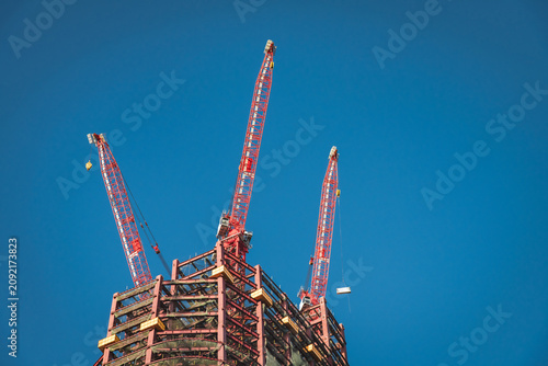 Photography Red luffing jib cranes lift heavy materials on rooftop of skyscraper structure i