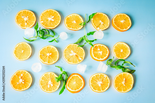 Obraz na płótnie Neatly arranged lemon slices with mint and ice cubes on a blue background, fresh