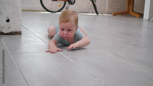 Infant actively explores the environment. Baby crawls diligently across the tiled floor in a spacious room with bicycles