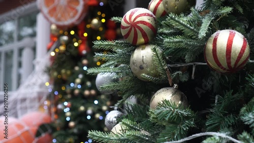 New Year's video card with fir branches decorated with garlands and Christmas balls in gold color in red stripes against the background of shimmering multi-colored garlands and giant tangerines i