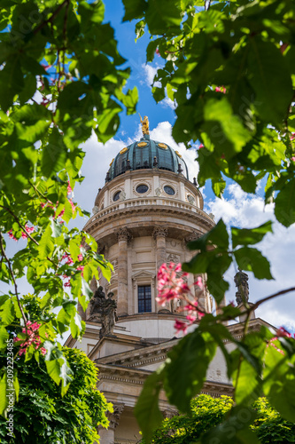 Gendarmenmarkt cathedral dome framed by green leaves in Berlin