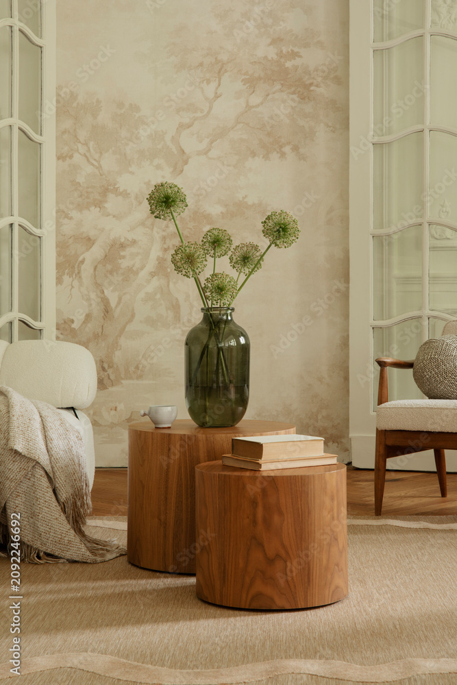 Obraz premium Inviting living room interior with contemporary wooden tables, a green glass vase with flowers, and natural decor elements