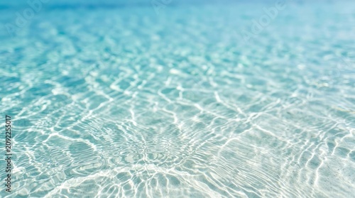 Turquoise ocean water surface with sunlight and ripples close up view