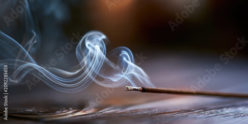 Close-up of incense stick burning with swirling smoke