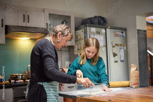 Grandmother teaching young girl to bake in a cozy home kitchen, sharing a quiet family moment