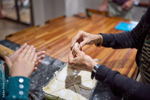 Grandmother teaching young girl to bake pie together in a warm family kitchen