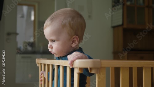An attentive, sweet baby watches from his crib, evoking associations with family, childhood happiness, and the innocence of a caring home
