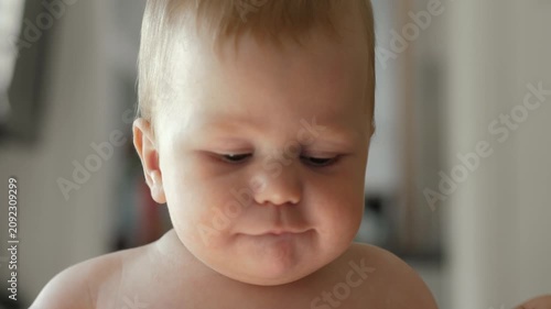 A happy baby peeks out from over the edge of a crib, shallow depth of field. The infant displays a curious and playful expression in a cozy and inviting home environment, close-up