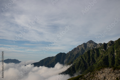 Fotografie Jagged mountain peak rising above a sea of clouds