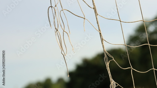 Fotografi Close-up detail of a damaged and frayed football goal net, symbolizing the end o