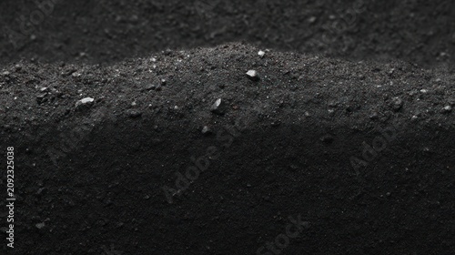 Fine grains of dark sand form undulating shapes evoking an intriguing atmosphere