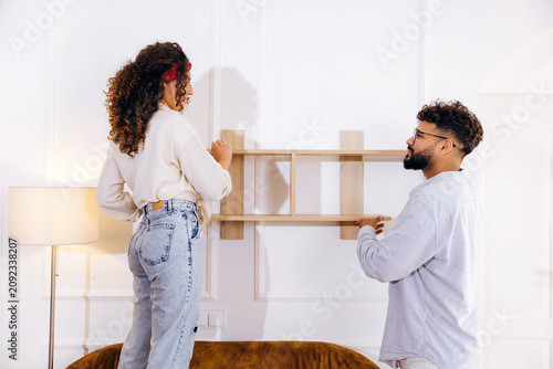 Fotografie Couple assembling wooden shelf for new home decor