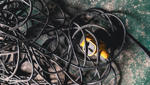 Tableau sur toile Messy tangled black electrical cables and a yellow extension socket on a dirty i