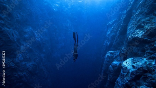 Professional Freediver Diving Deep into a Narrow Underwater Canyon Fissure in Crystal Clear Blue Water