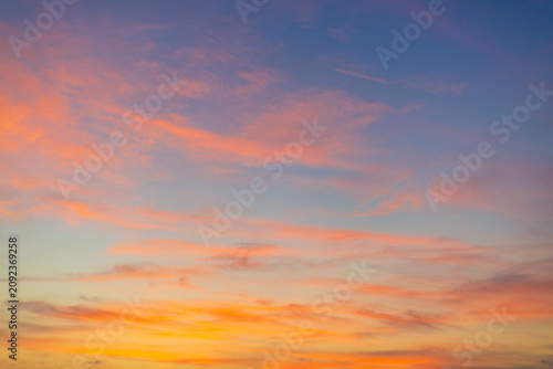 Beautiful Vibrant Sunset Sky with Colorful Clouds,A stunning, colorful sunset sky featuring a gradient of deep blue, bright orange, and golden yellow hues with soft, wispy clouds scattered across.