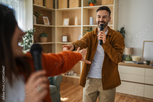 Foto Happy couple singing karaoke at home entertaining