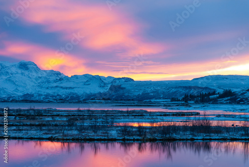 Winter sunset over Þingvallavatn in Þingvellir National Park Iceland with colorful reflections snow covered mountains and a tranquil volcanic lake