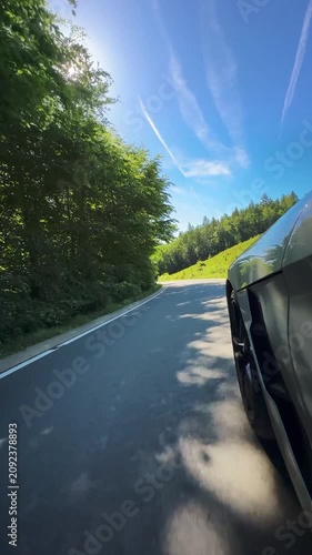 convertible car in sunny nature on a bright summer day. wide angle pursuit shot - vertical video for reels and story