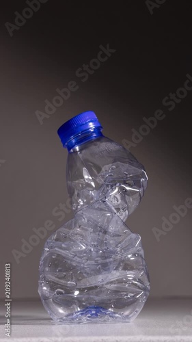 Stop motion animation of a plastic PET bottle compressing and returning to its original shape, demonstrating material elasticity, recyclable packaging and sustainability concept
