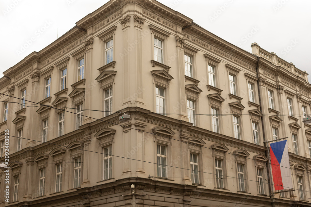 Obraz premium Neoclassical corner building with ornate window pediments and pilasters, painted in beige tones. Tall rectangular windows with white frames